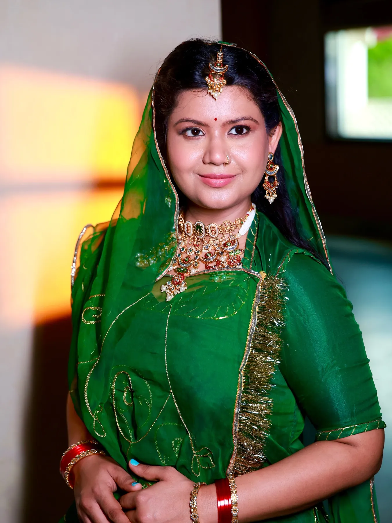 Guest in an emerald green saree with gold jewellery and warm daytime makeup