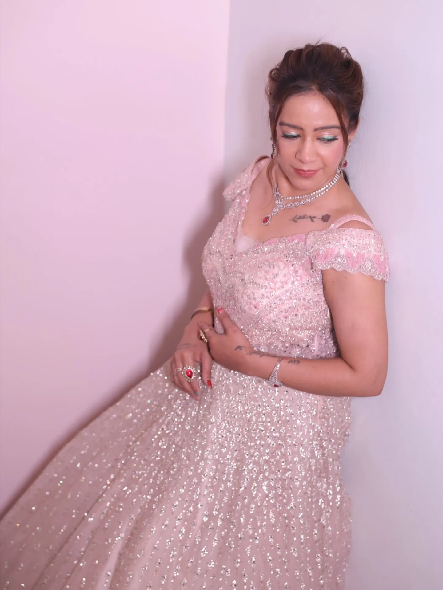 Blush pink sequinned gown with an updo and soft rose-toned party makeup
