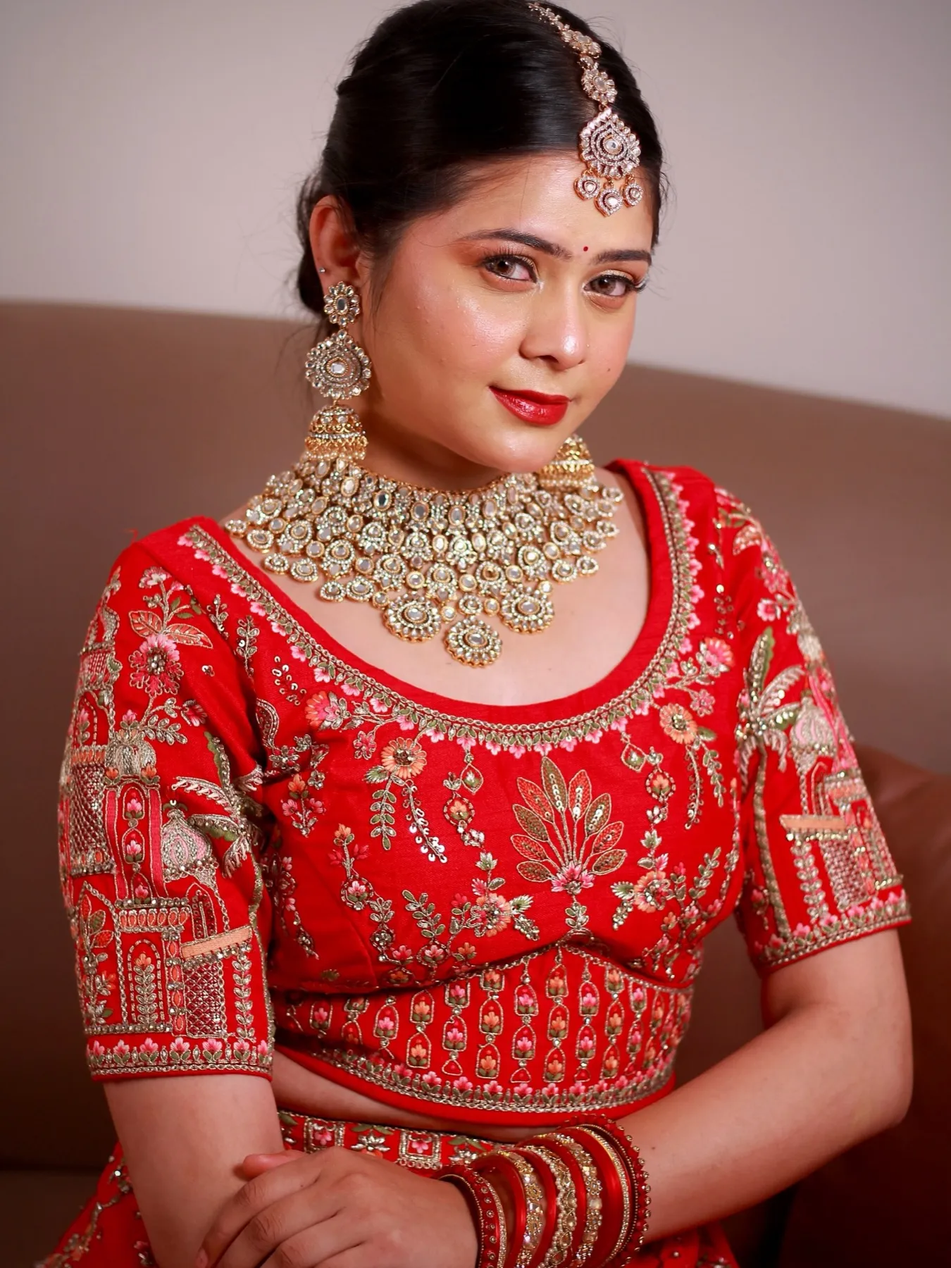 Close-up of a bride in a red embroidered lehenga with kundan jewellery and a bold red lip