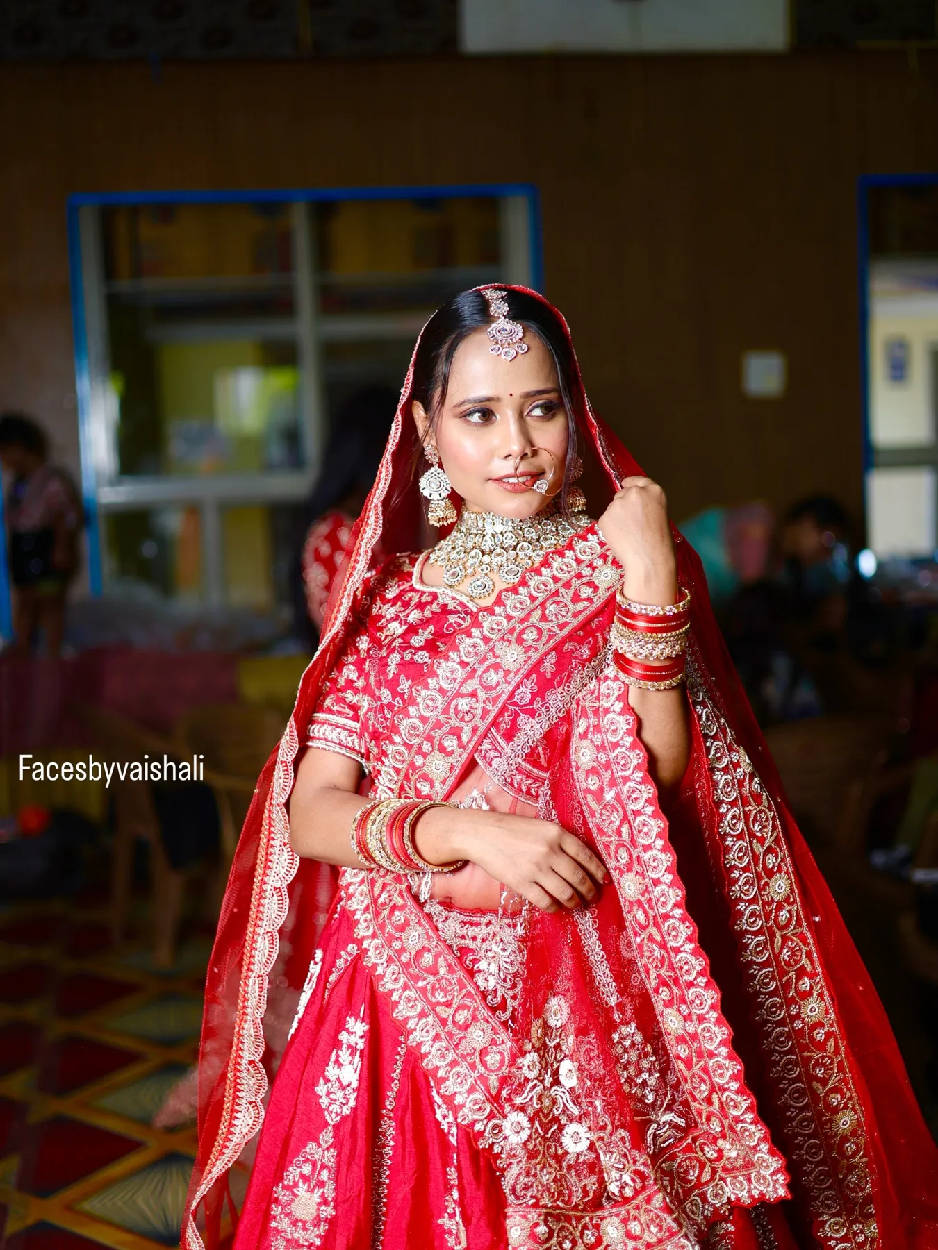 Full-length bride in a red and pink lehenga at her wedding venue